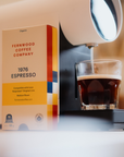 Fernwood Coffee Company 1976 Espresso package next to an espresso machine and glass of coffee.