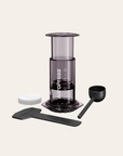 AeroPress coffee maker with components on a light beige background