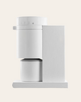 A matte white coffee grinder with a sleek design, featuring a digital display and a removable bean container.