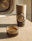 Portable espresso maker and a cup of coffee on a wooden surface