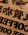 A close up of block print hand carved into wood with the word 'coffee' visible.
