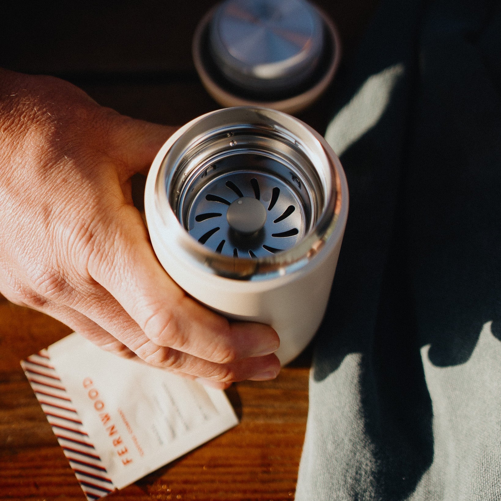 A top down view into a travel mug with a pouch of instant in the background