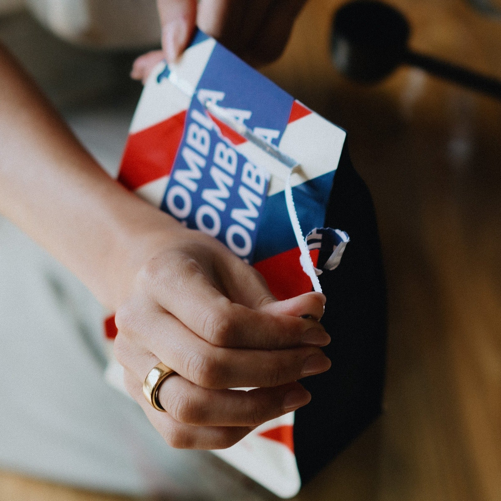 A person ripping open a bag of single origin Colombian coffee at a glass coffee table