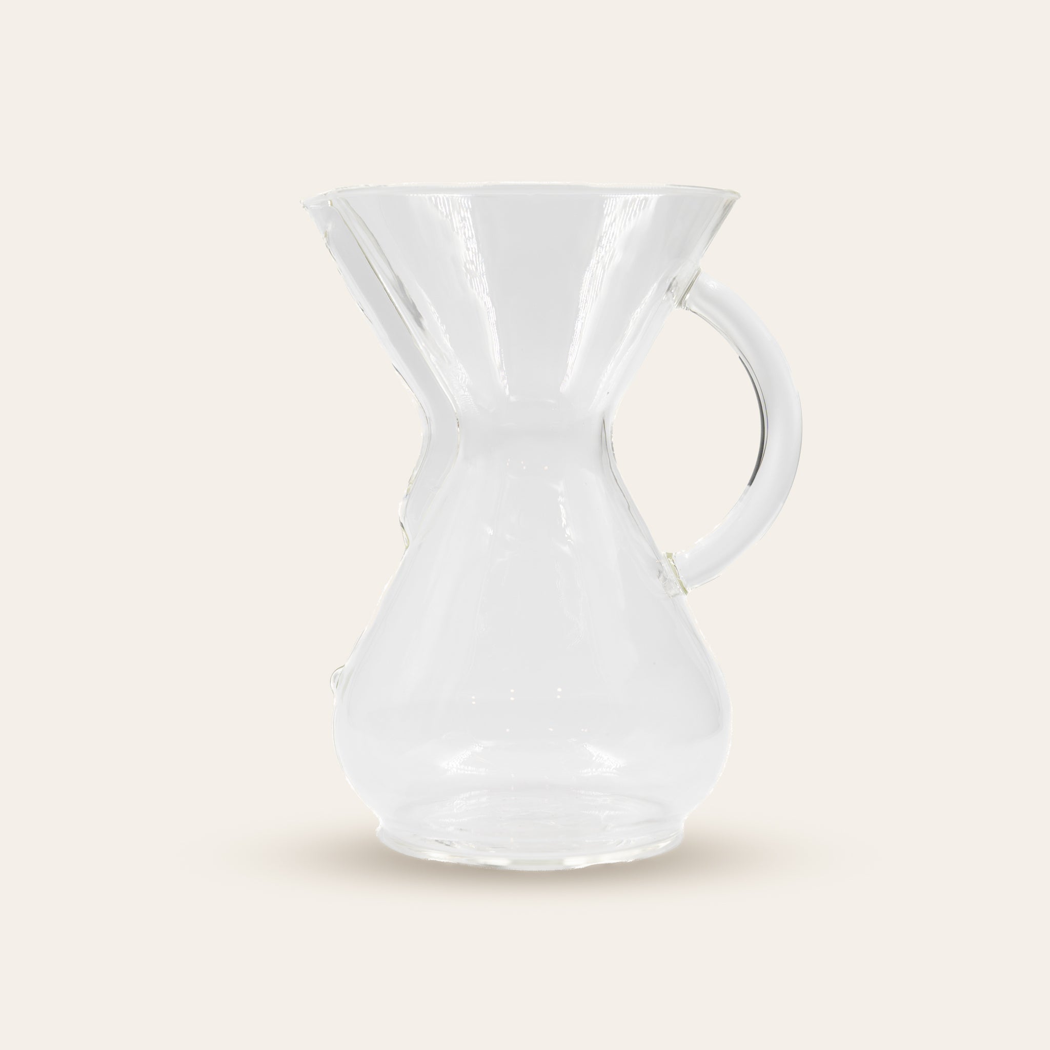 Clear glass Chemex Brewer with handle on a beige background