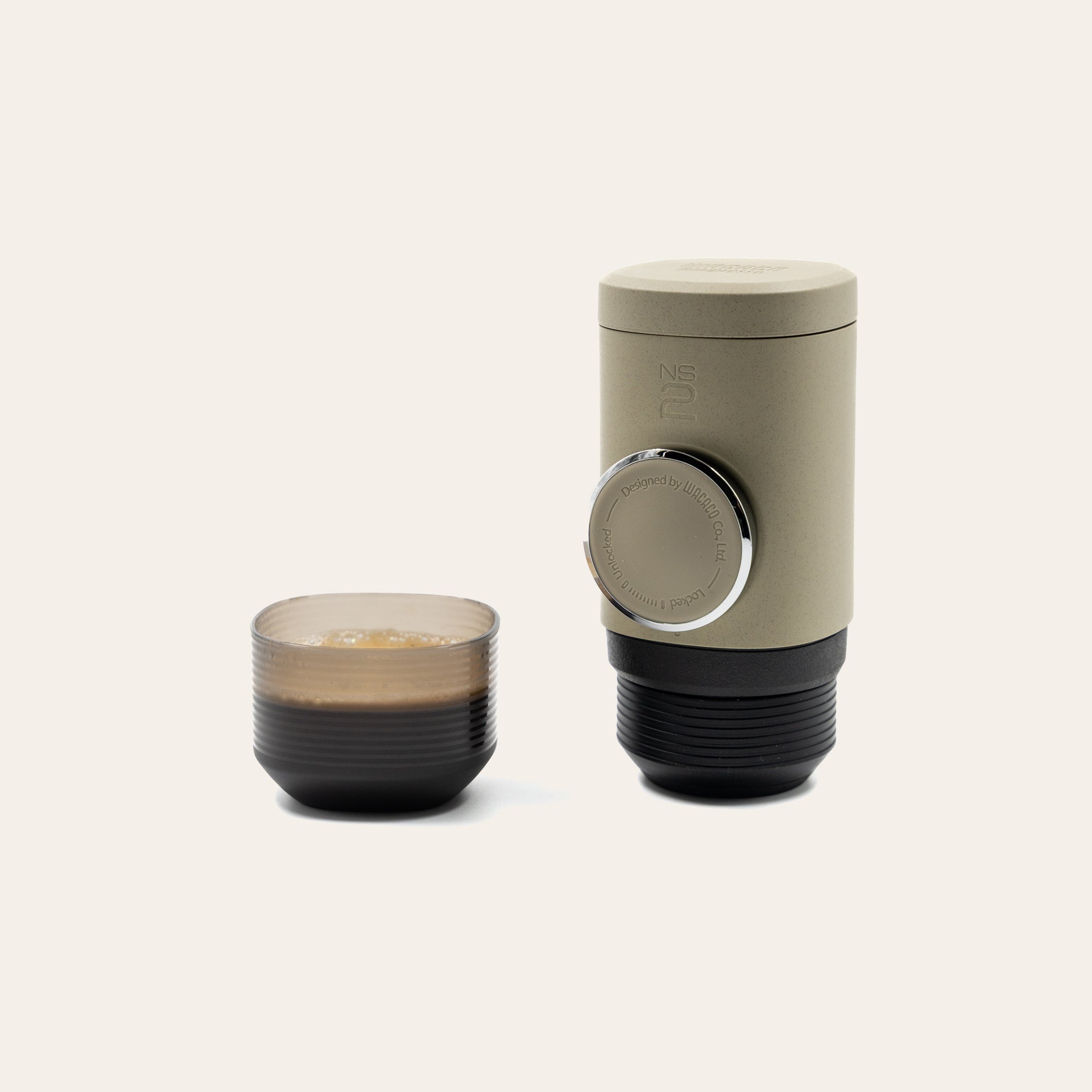 Minipresso and brewed coffee in attached cup sitting on a beige background