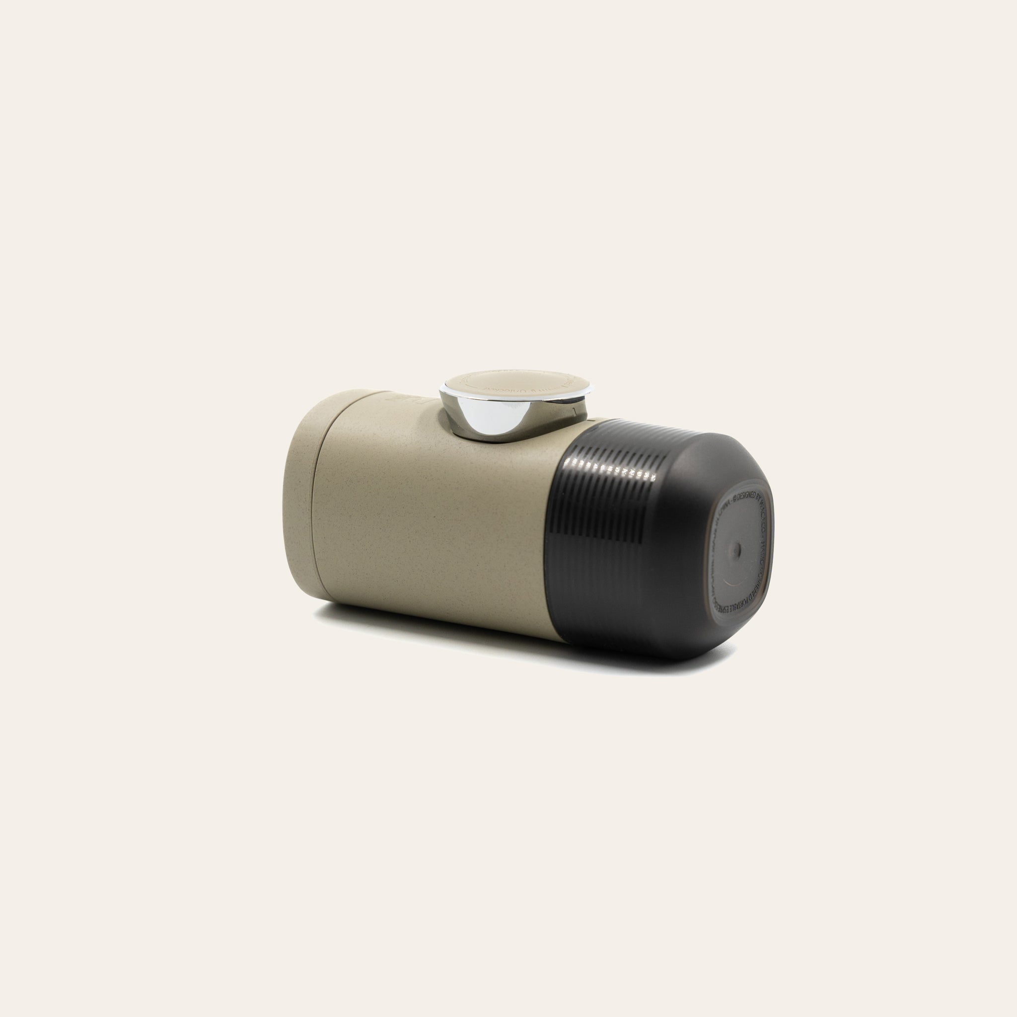 Minipresso laying on its side on a beige background