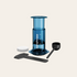Blue AeroPress coffee maker with accessories on a beige background