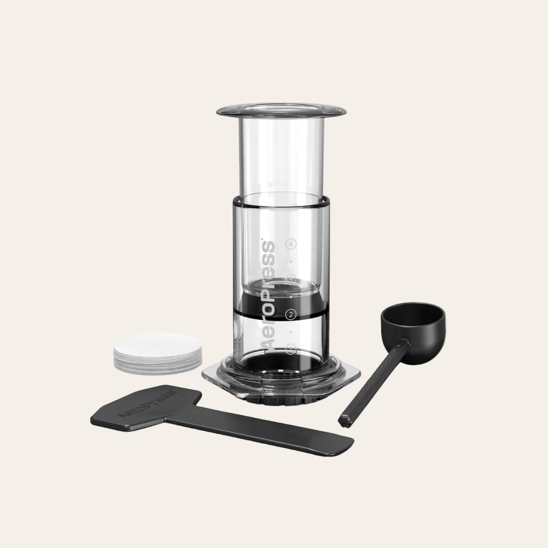 AeroPress coffee maker with components on a light beige background