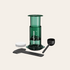 Green AeroPress coffee maker with components on a beige background