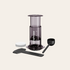AeroPress coffee maker with components on a light beige background