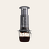 AeroPress coffee maker with coffee being brewed on a light beige background