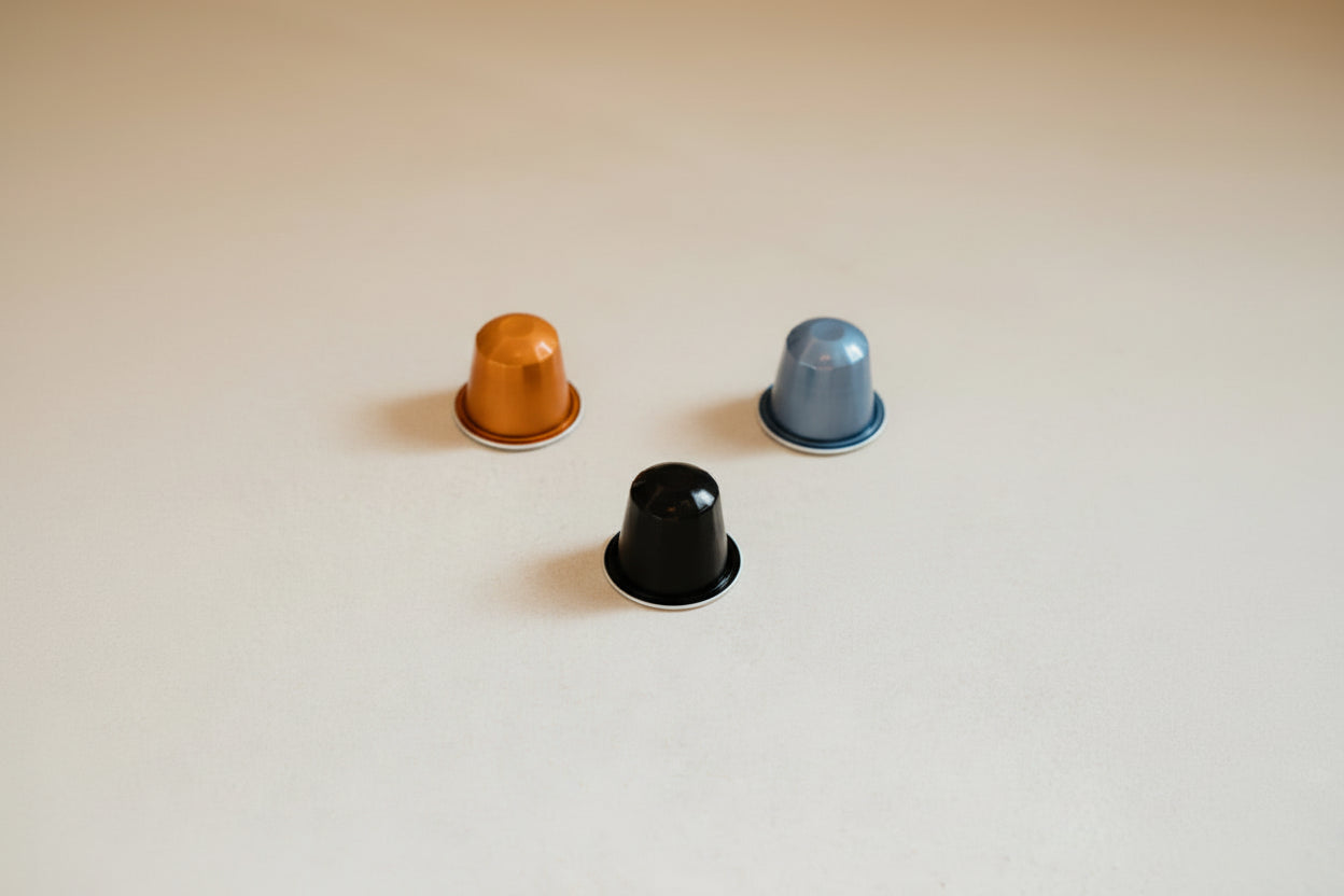Three Coffee capsules sitting on a kitchen counter.