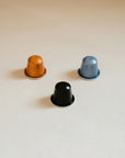 Three Coffee capsules sitting on a kitchen counter.