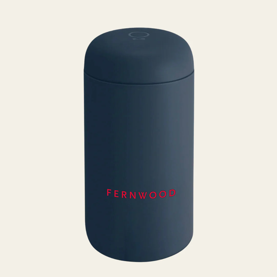 Navy blue travel mug with 'FERNWOOD' branding on a light beige background