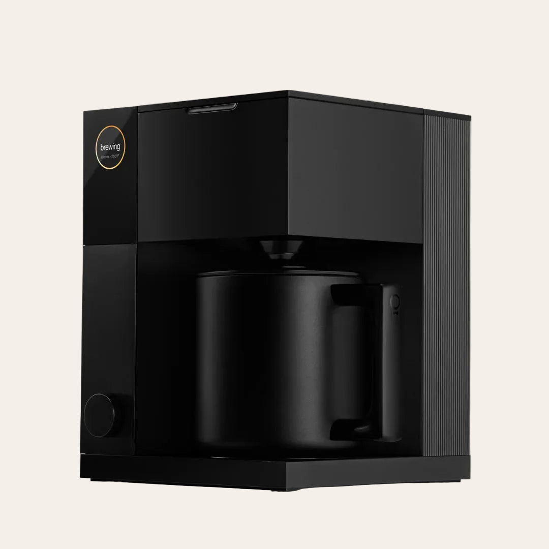 Black coffee maker in a box with a brand logo on a beige background