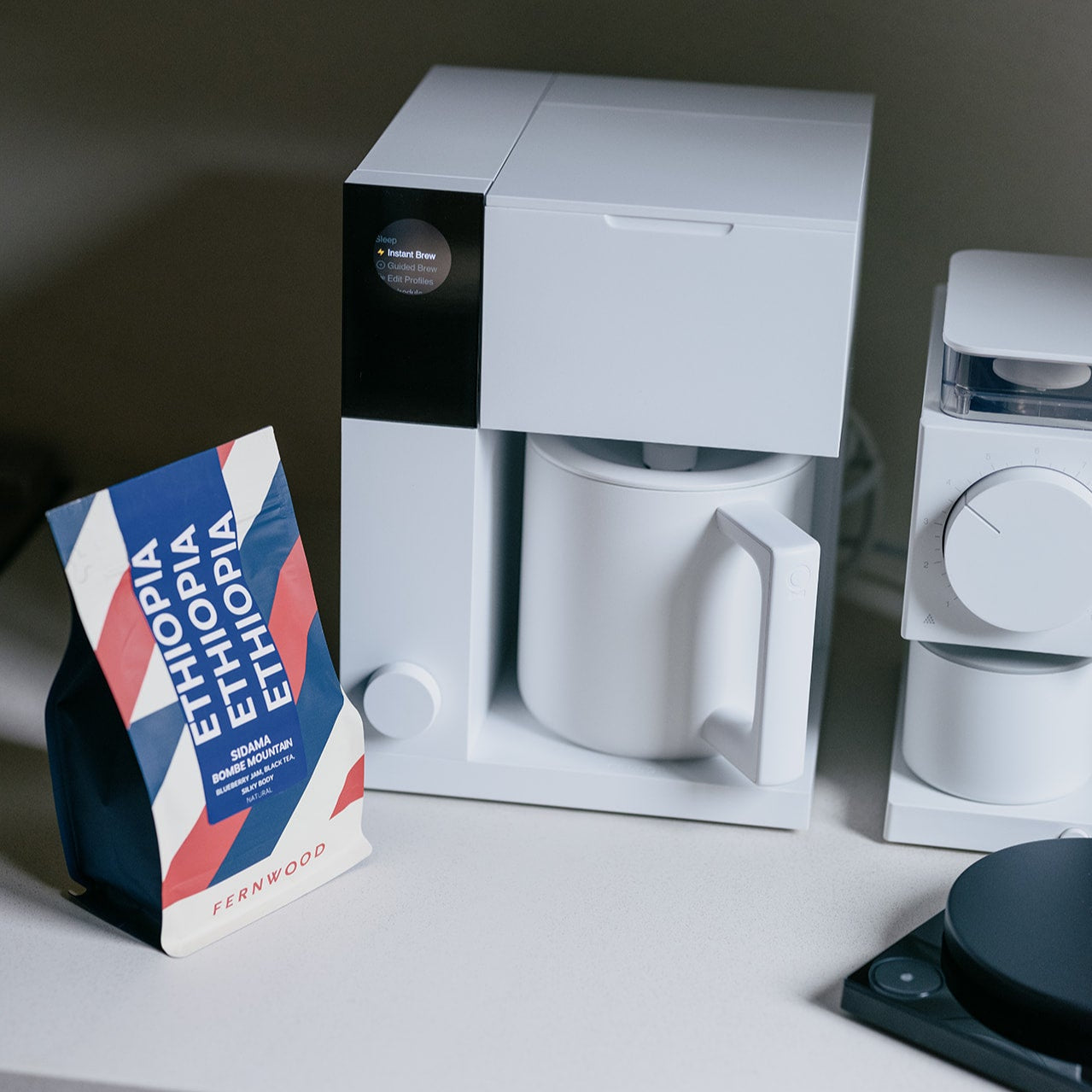 White coffee maker with a mug and Ethiopia coffee package on a gray kitchen surface