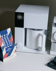 White coffee maker with a mug and Ethiopia coffee package on a gray kitchen surface