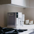 White coffee maker on a kitchen counter with a neutral background