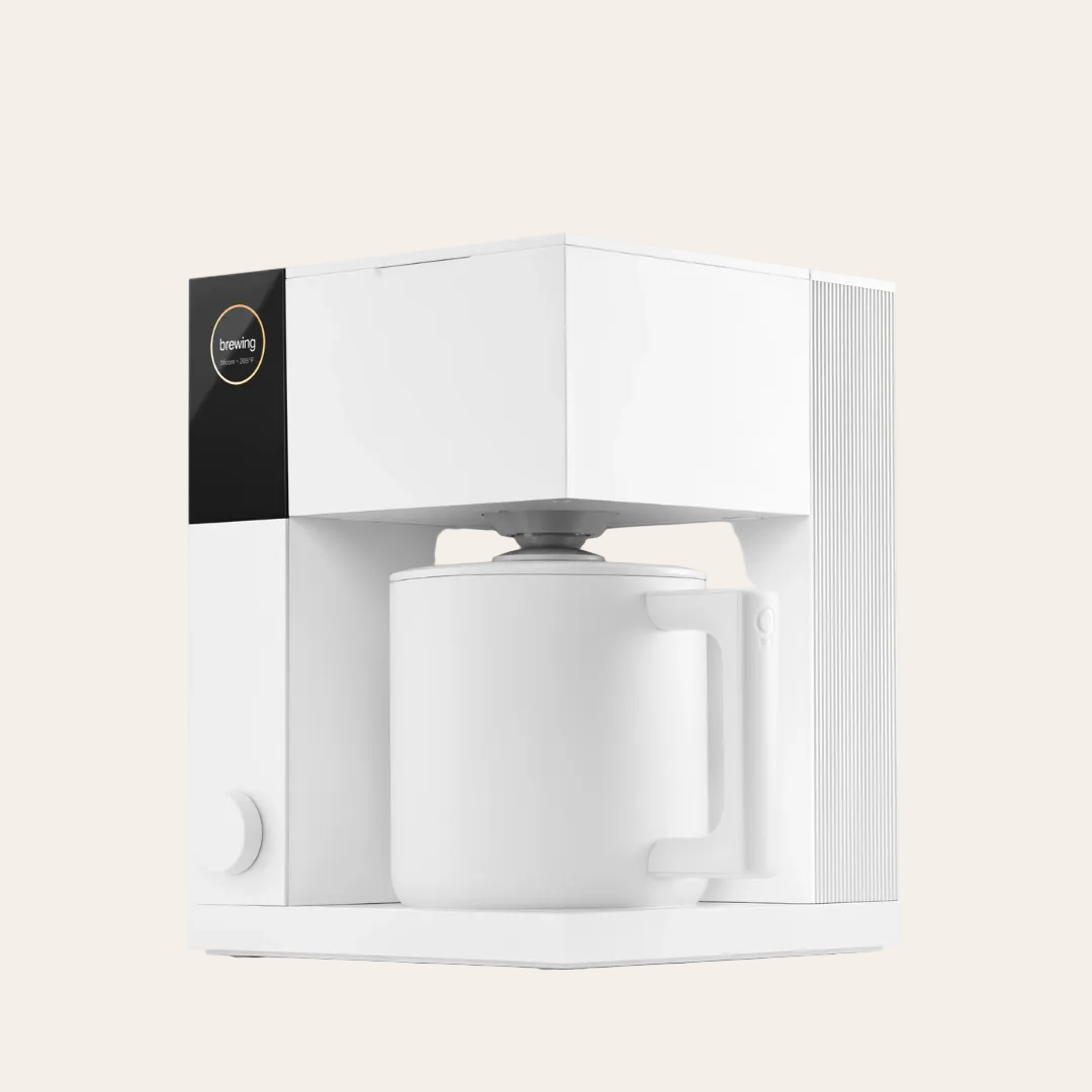 A matte white FELLOW Aiden Precision Coffee Maker with a single cup placed inside, set against a plain background.