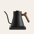 Black electric kettle with wooden handle on a beige background