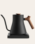 Black electric kettle with wooden handle on a beige background