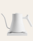 An electric pour-over kettle in matte white color with a precision spout, control panel, and a long handle.