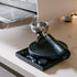 Coffee tamping device on a kitchen counter with a coffee machine in the background