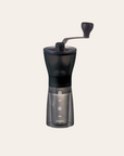 Black manual coffee grinder with crank lever-style handle.