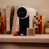 White coffee machine on a counter with books and a coffee pod in the foreground