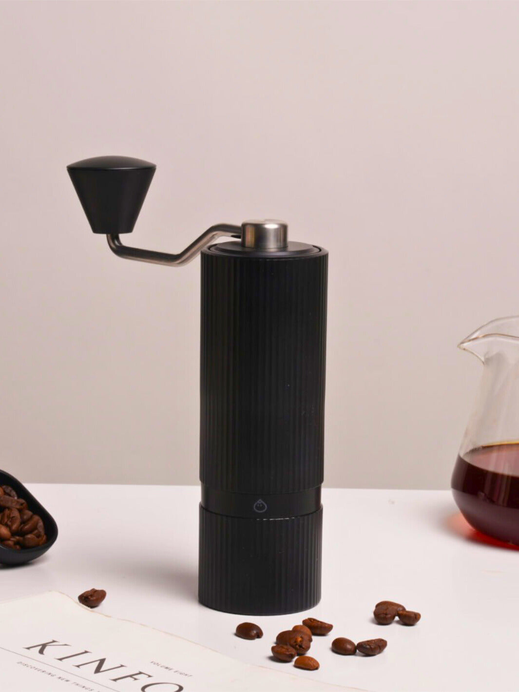 Black Nuttii Goosey hand grinder with coffee beans and a glass server