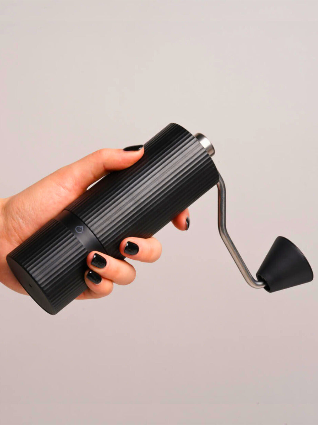 Hand holding a black Nuttii Goosey hand grinder sideways