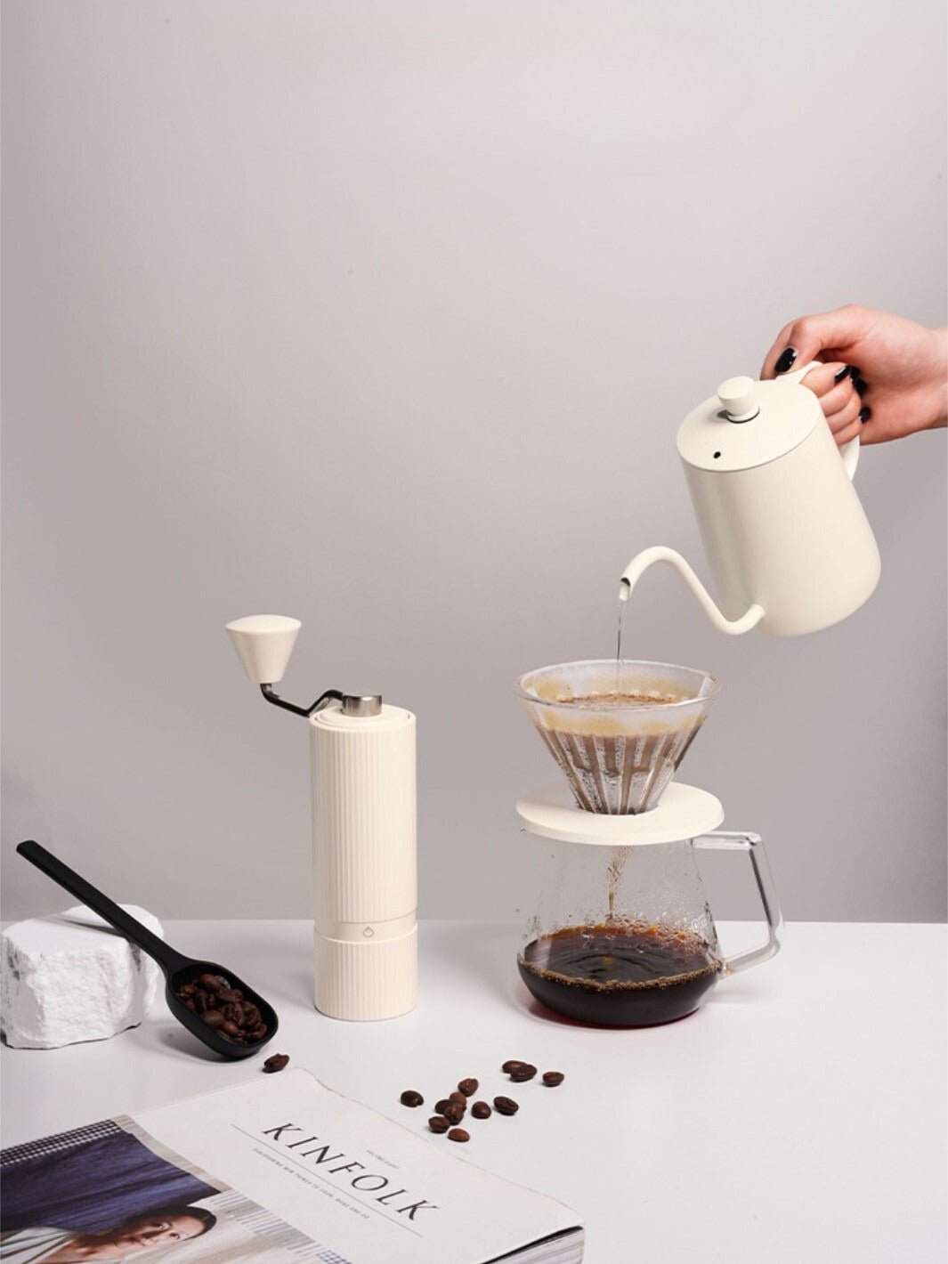 Off-white Nuttii Goosey grinder beside a pour-over brewer and gooseneck kettle