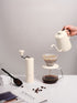 Off-white Nuttii Goosey grinder beside a pour-over brewer and gooseneck kettle