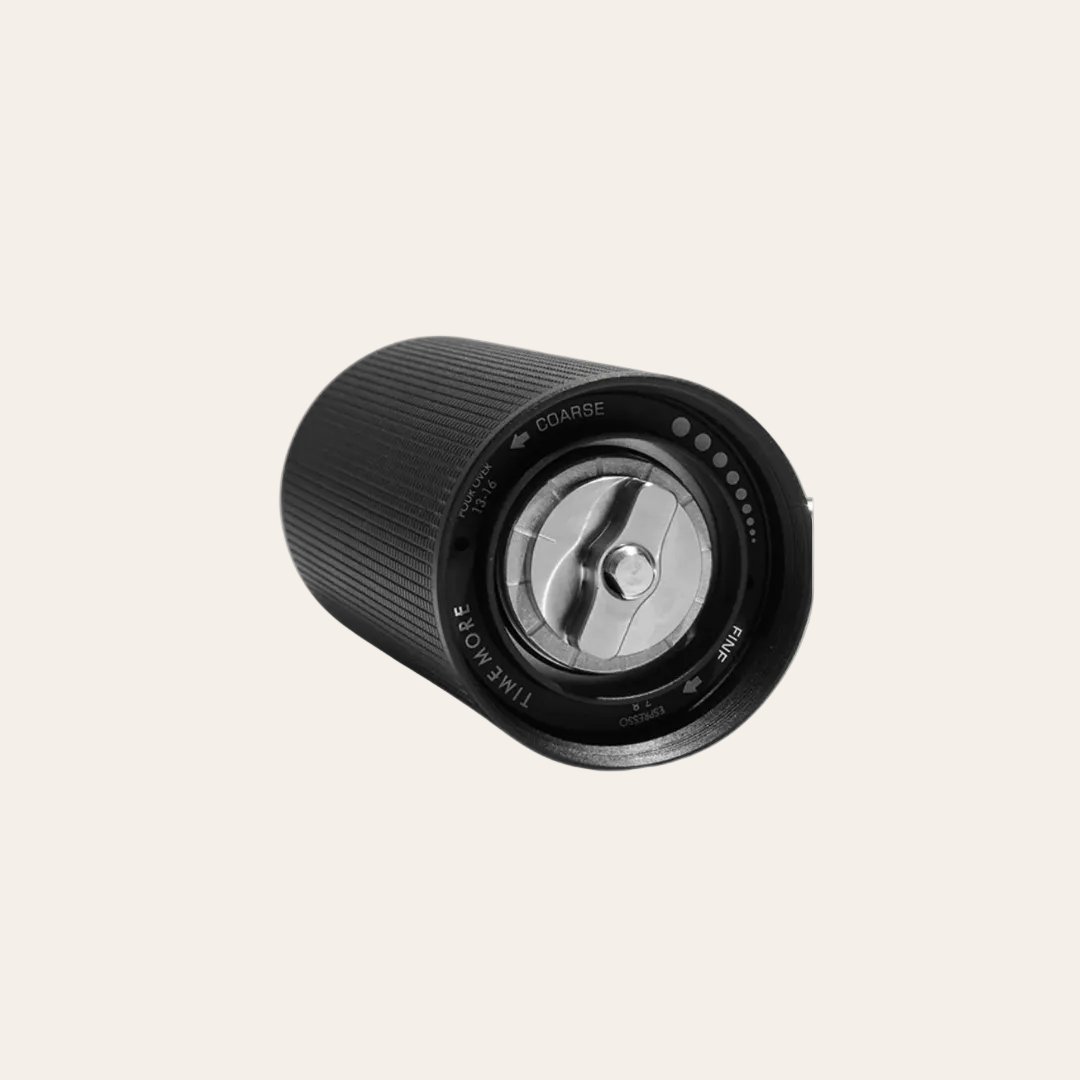 Black manual coffee grinder bottom on beige background