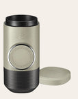 Hand pump espresso brewer with cap off for travel on a beige background