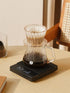 Coffee brewing setup with a glass carafe on a digital scale on a wooden table.