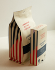 A bag of Fernwood Blend beans and a box of Fernwood Blend Capsules paired together on a white counter.
