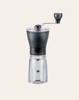 Coffee grinder with clear body and black top on a white background