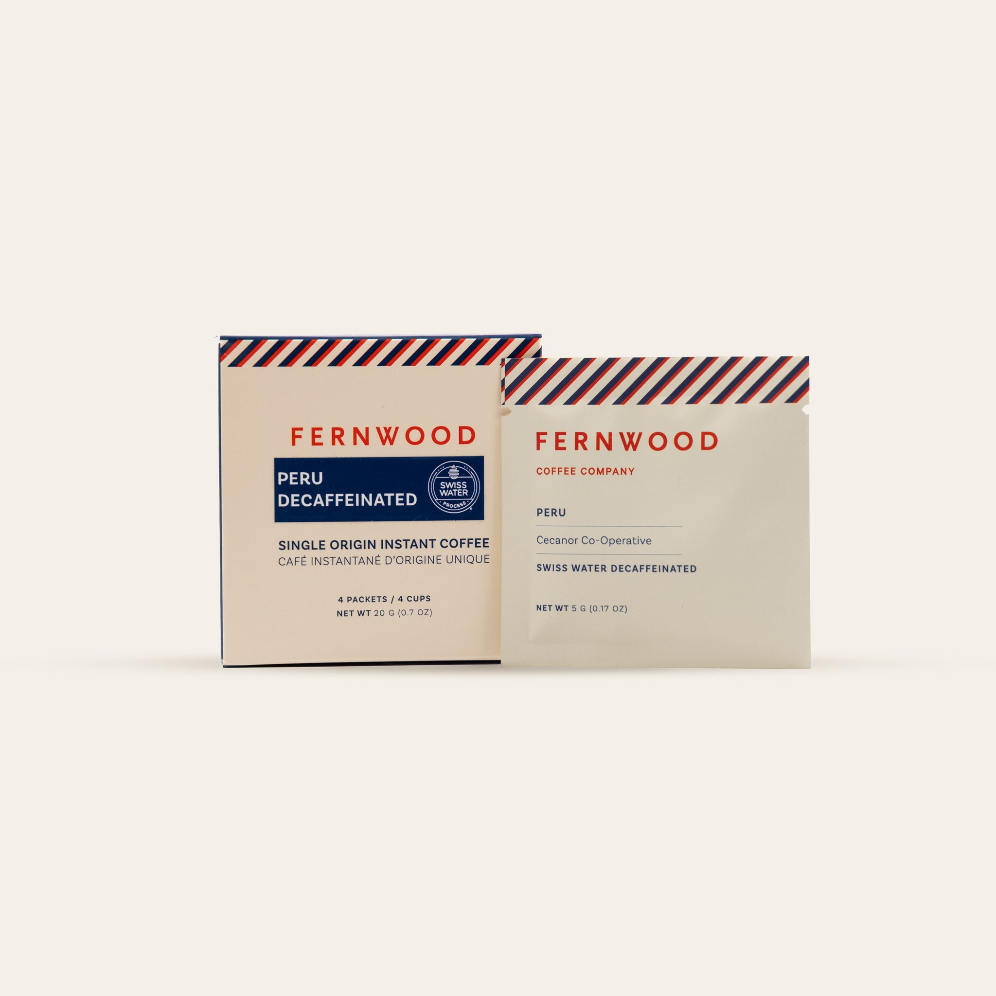 A box and pouch of Fernwood Peru Decaf instant coffee on a beige background.