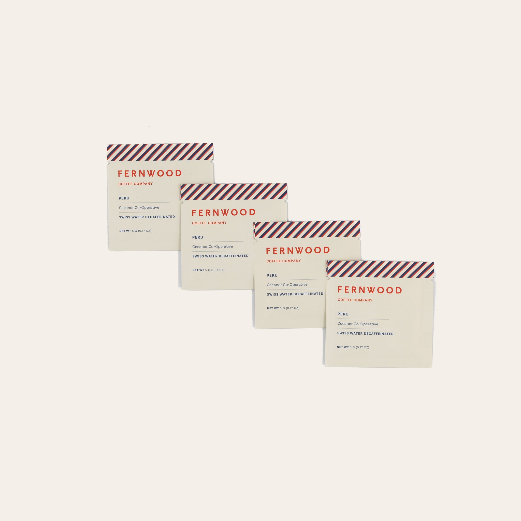 Four Fernwood coffee packages of Peru Decage instant on a beige background.