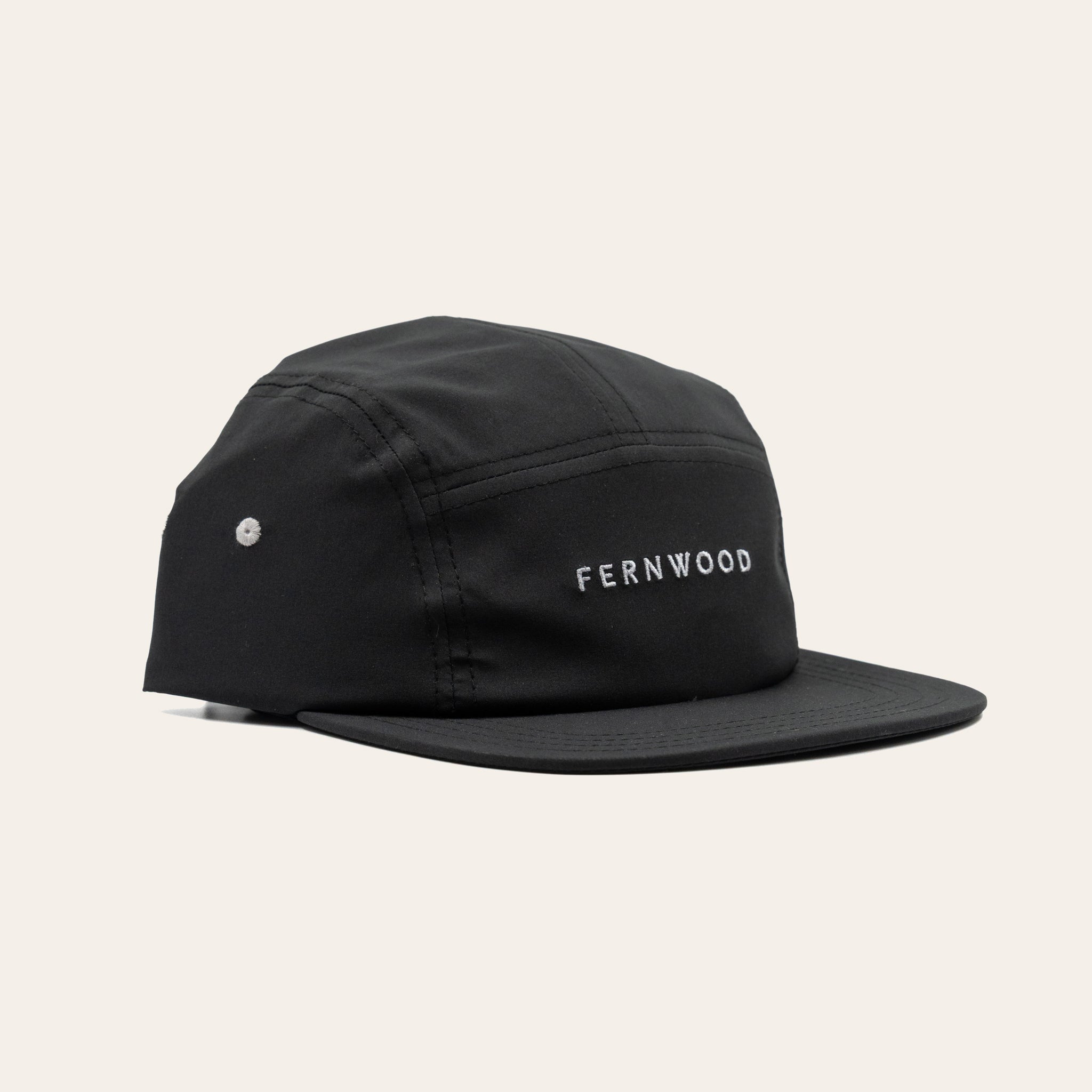 Black cap with 'FERNWOOD' branding on a beige background
