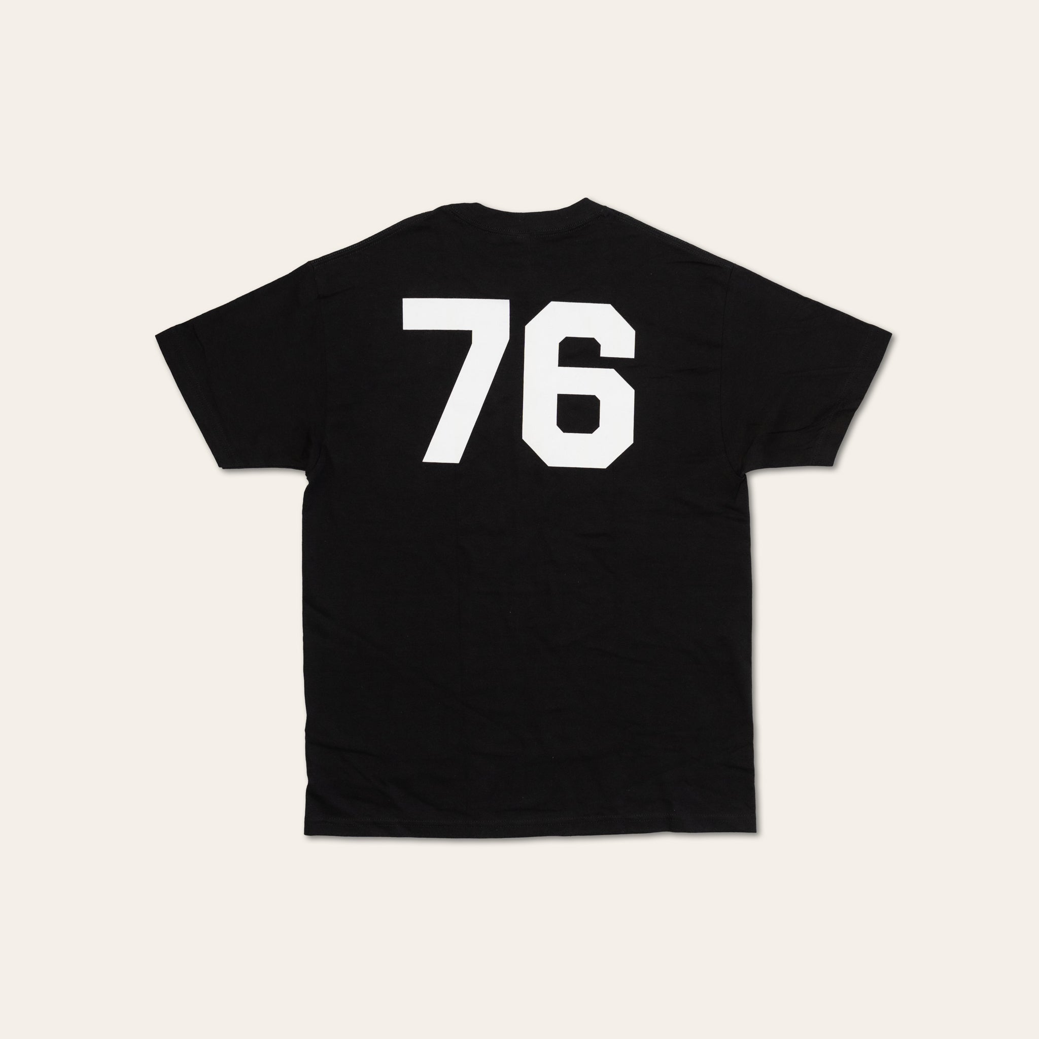 Back of a white tshirt with large 76 numbering in black on a beige background