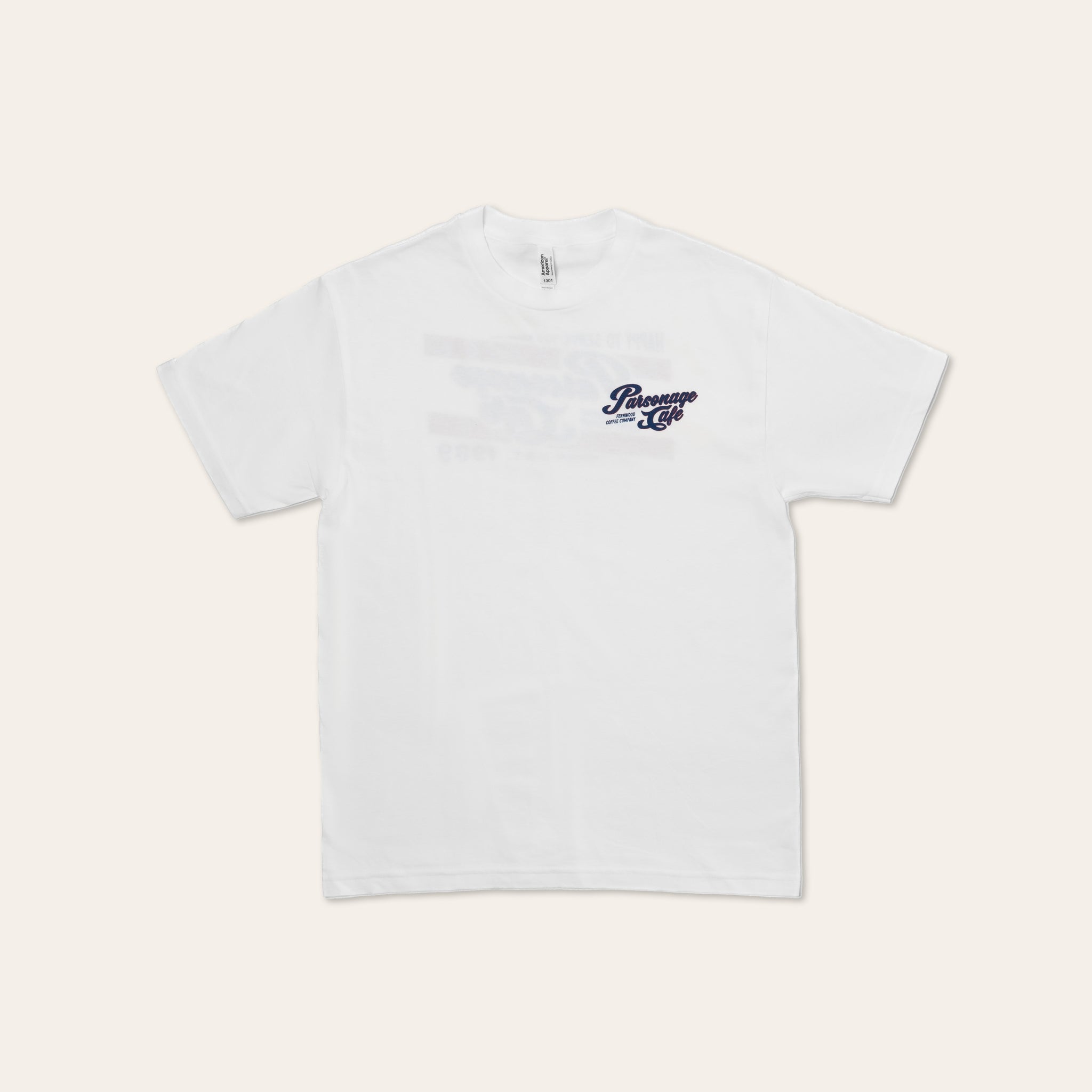 White t-shirt with a small Parsonage Cafe logo on the chest against a light beige background