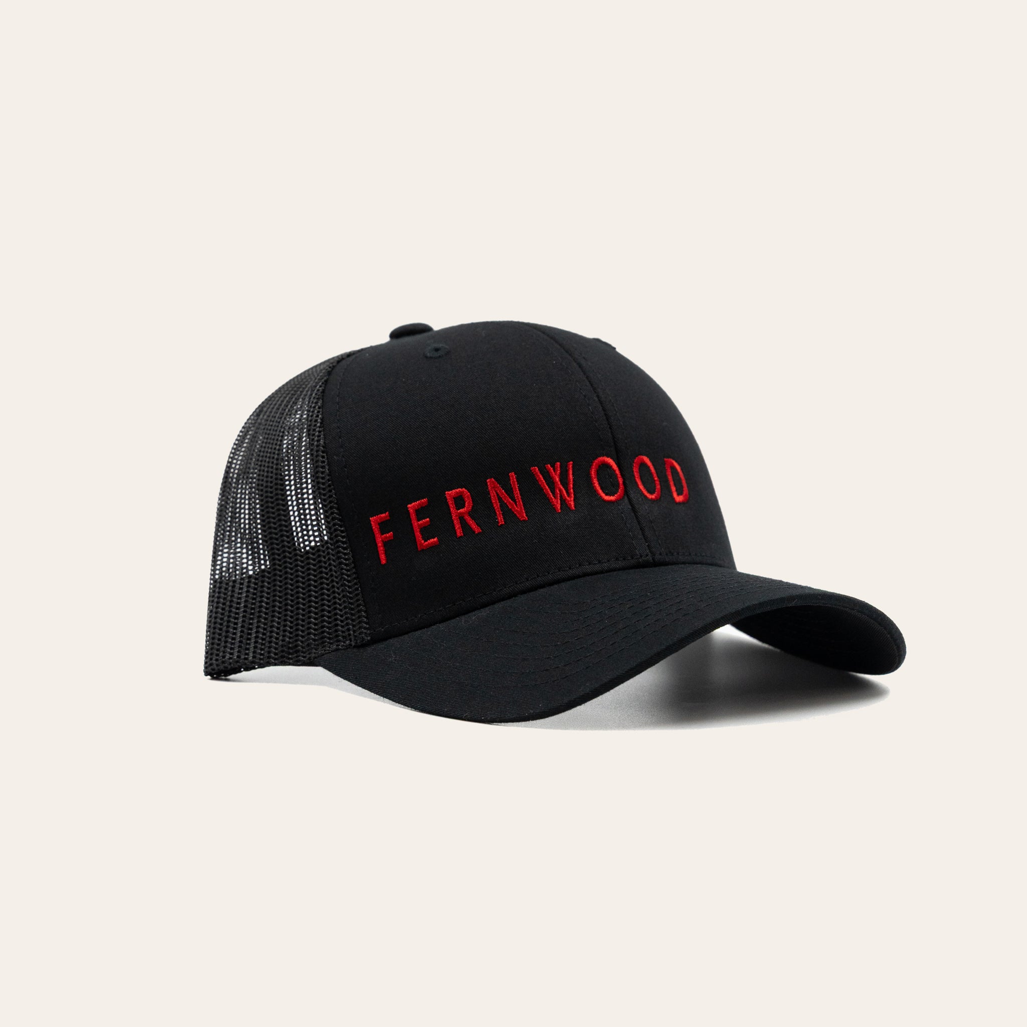 Black cap with 'FERNWOOD' text on a beige background