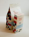 A bag of Mile Zero beans paired with a box of capsules on a white counter.