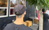 Person wearing a cap with a tattoo on the back of their neck, standing outdoors.