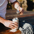 Person pulling flow control piece from inside of a beige travel mug outdoors.
