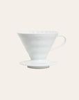 A white ceramic Hario V60-02 dripper, designed for brewing coffee, displayed against a plain background.