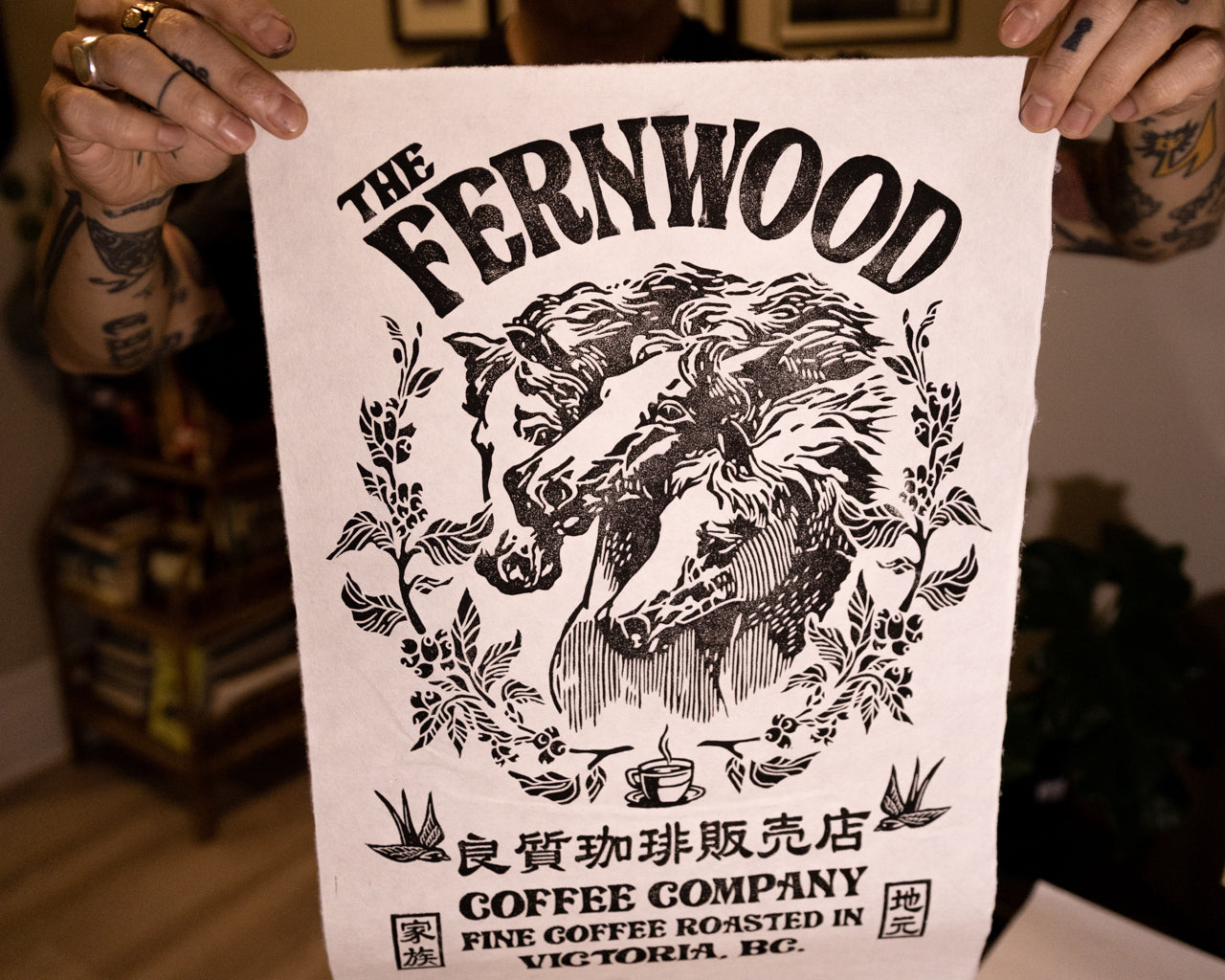 A person holding up a black and white print of a horse with the text 'THE FERNWOOD COFFEE COMPANY' displayed at the top.