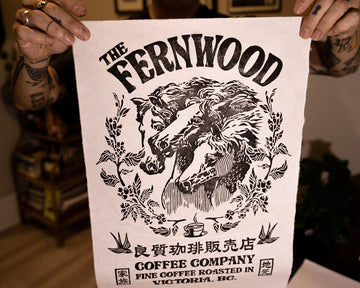 A person holding up a black and white print of a horse with the text 'THE FERNWOOD COFFEE COMPANY' displayed at the top.